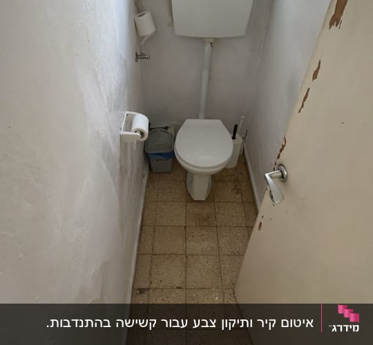שירותים עם קירות מתקלפים ורצפה מרוצפת